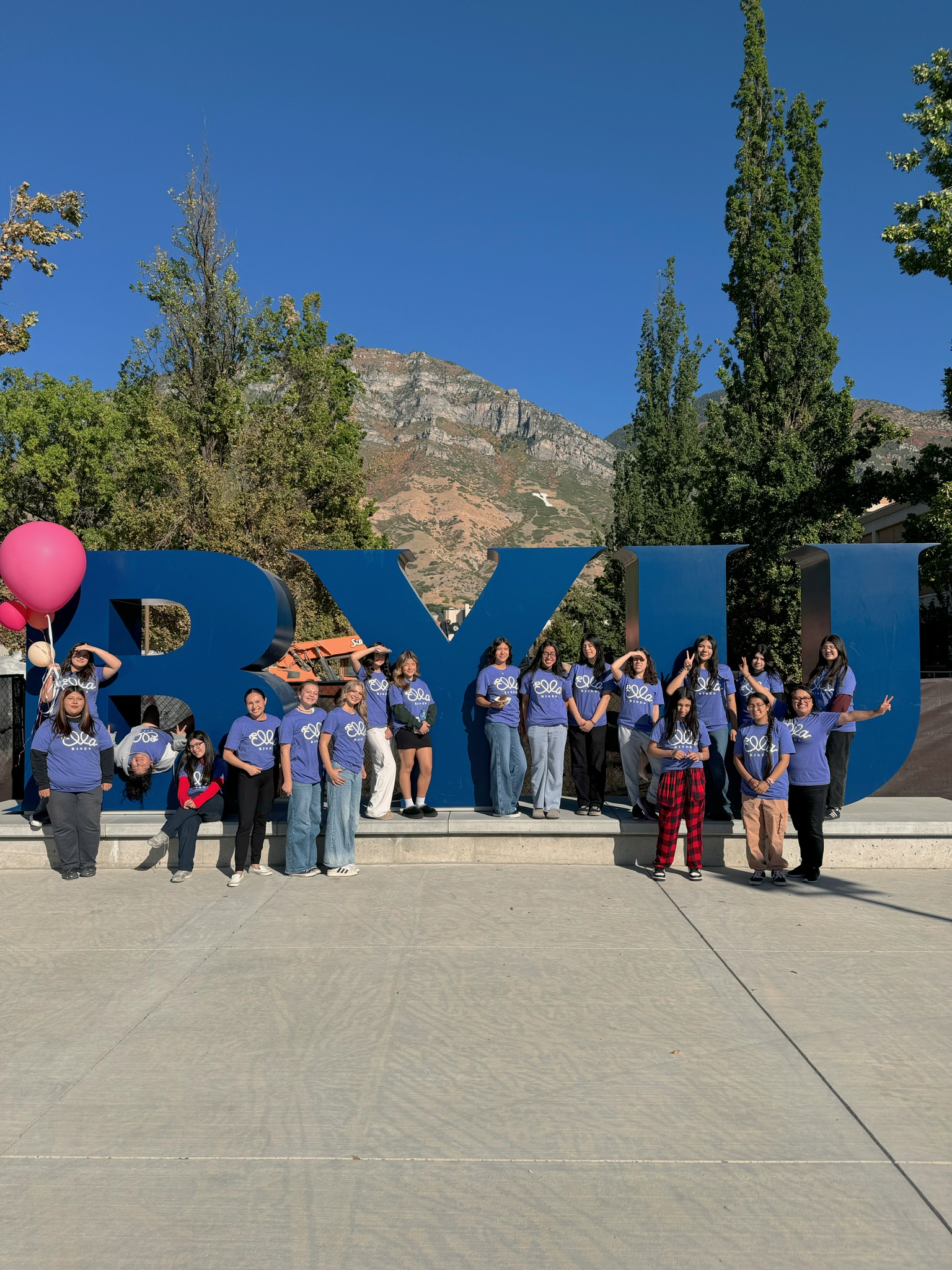Group of Ella Rises students in purple shirts posing in front of the BYU letters and mountains